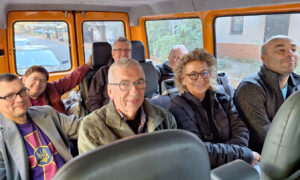 Beate Müller-Gemmeke sitzt mit mehreren Menschen in einem Transportfahrzeug. Die Gruppe wirkt entspannt und lächelt in die Kamera.