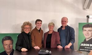 Gruppenfoto von Beate Müller-Gemmeke mit Jaron Immer und den Landtagsabgeordneten Cindy Holmberg und Thomas Poreski. Alle stehen an einem Tisch und lächeln in die Kamera. Im Hintergrund sind Wahlkampfplakate zu erkennen.