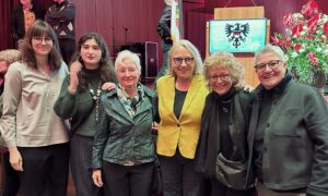 Gruppenfoto mit Birgit Groner, Beate Müller-Gemmeke und weiteren Frauen während des Bürgerempfangs in Reutlingen. Die Frauen lächeln in die Kamera, im Hintergrund ist die Bühne mit Rednerpult und Dekoration zu sehen.