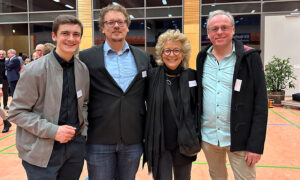 Vier Personen stehen lächelnd in einer Turnhalle nebeneinander. Links steht der grüne Bundestagskandidat Jaron Immer und in der Mitte Beate Müller-Gemmeke. Alle tragen Namensschilder, die Atmosphäre wirkt freundlich und offen.