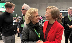 Beate Müller-Gemmeke und Franziska Brantner stehen sich zugewandt in einer offenen, freundlichen Unterhaltung. Beide tragen Namensschilder der Veranstaltung und lächeln sich an. Im Hintergrund sind weitere Teilnehmer*innen der Konferenz zu sehen.