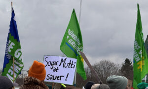 Ein Schild mit der Aufschrift „Sogar Mutti ist sauer!“ ragt aus der Menge hervor. Dahinter eine grüne Grünen-Fahne und viele Demonstrierende.