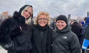 Beate Müller-Gemmeke lächelt auf der Demo gemeinsam mit zwei jungen Menschen in schwarzen Jacken. Im Hintergrund sind weitere Demonstrierende.