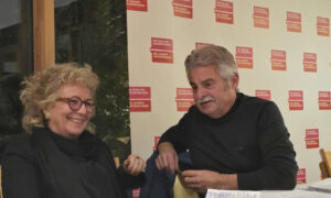 Beate Müller-Gemmeke (MdB, Bündnis 90/Die Grünen) sitzt im Gespräch mit Rainer Knauer (Die Familienunternehmer). Beide lachen, während sie sich austauschen. Im Hintergrund eine Wand mit den roten Logos von „Die Familienunternehmer“ und „Die Jungen Unternehmer“.