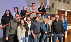 Eine weitere Gruppe von BPA-Teilnehmenden, darunter Beate Müller-Gemmeke, steht und sitzt auf einer Treppe im Bundestag. Männer und Frauen verschiedener Altersgruppen lächeln in die Kamera. Die Gruppe ist bunt gemischt und strahlt eine offene Atmosphäre aus.