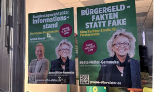 Zwei Wahlplakate von Bündnis 90/Die Grünen hängen in einem Innenraum. Links: „Bundestagswahl 2025: Informationsstand“ mit einem Foto von Jenifer Howel und Beate Müller-Gemmeke. Rechts: „Bürgergeld – Fakten statt Fake“ mit einem Bild von Beate Müller-Gemmeke. Die Plakate enthalten Veranstaltungstermine und QR-Codes.