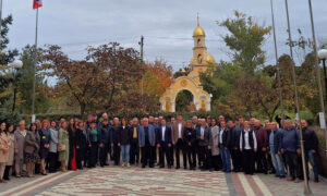 Eine große Versammlung von Menschen, darunter die Delegation aus Deutschland und lokale Vertreter:innen, steht vor einer Kirche mit goldener Kuppel. Ukrainische Flaggen sind im Bild.